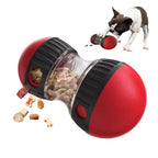 Red and black dog toy with food compartments and a dog playing with it.