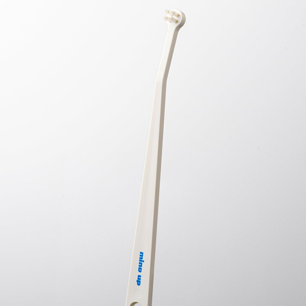 White toothbrush with a curved handle on a light gray background