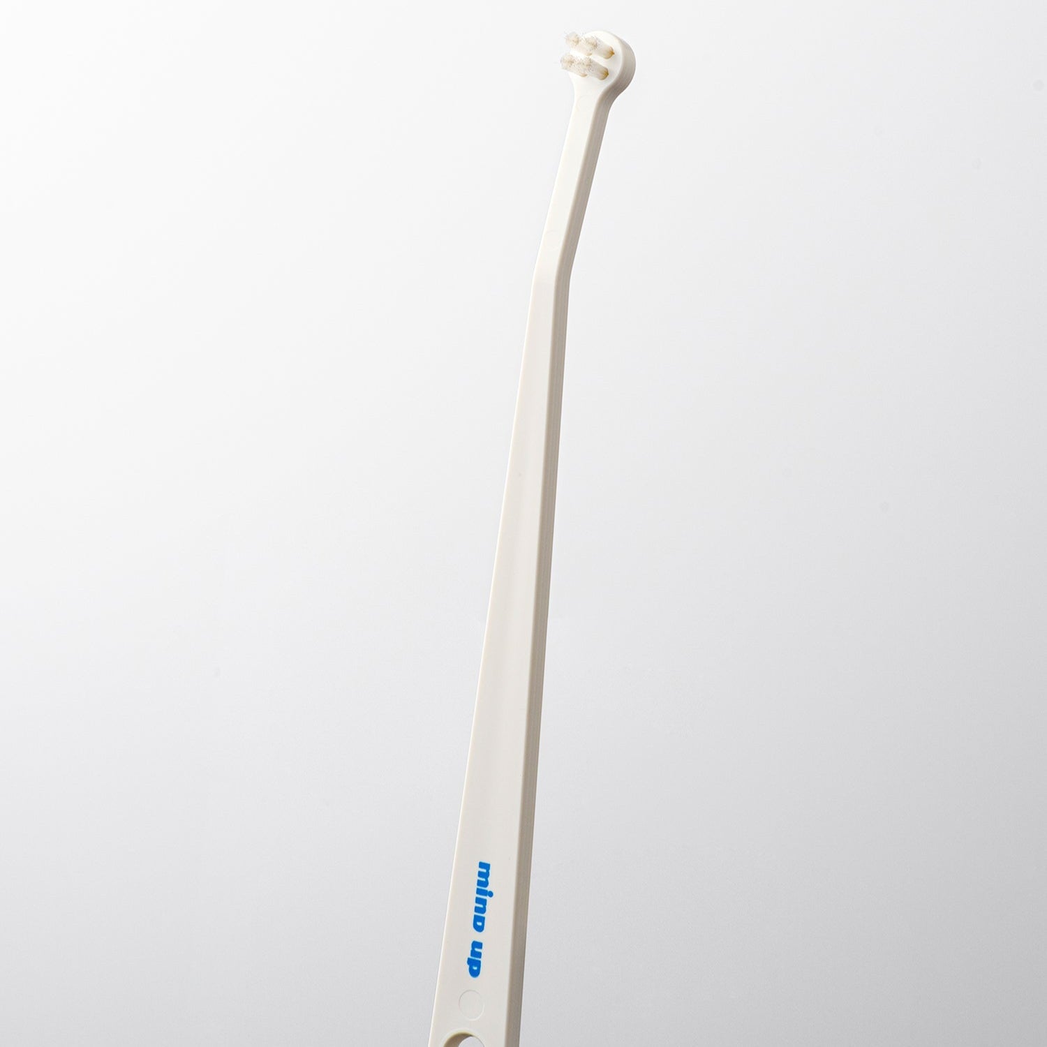 White toothbrush with a curved handle on a light gray background
