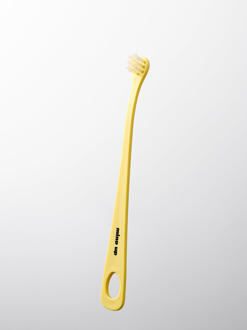 Yellow dog toothbrush with a white handle on a light gray background