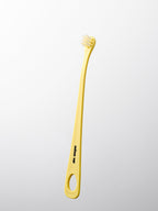 Yellow dog toothbrush with a white handle on a light gray background