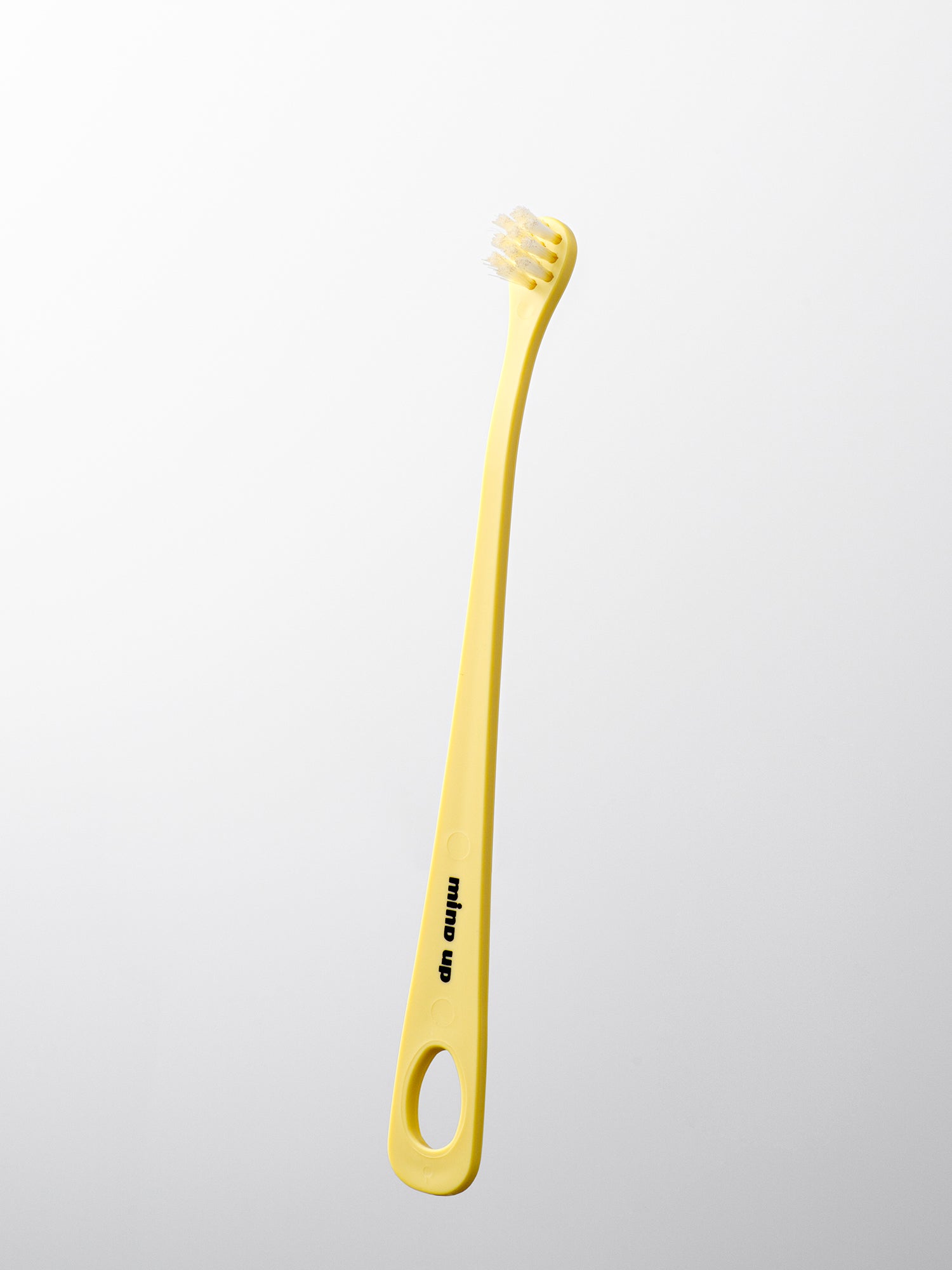 Yellow dog toothbrush with a white handle on a light gray background