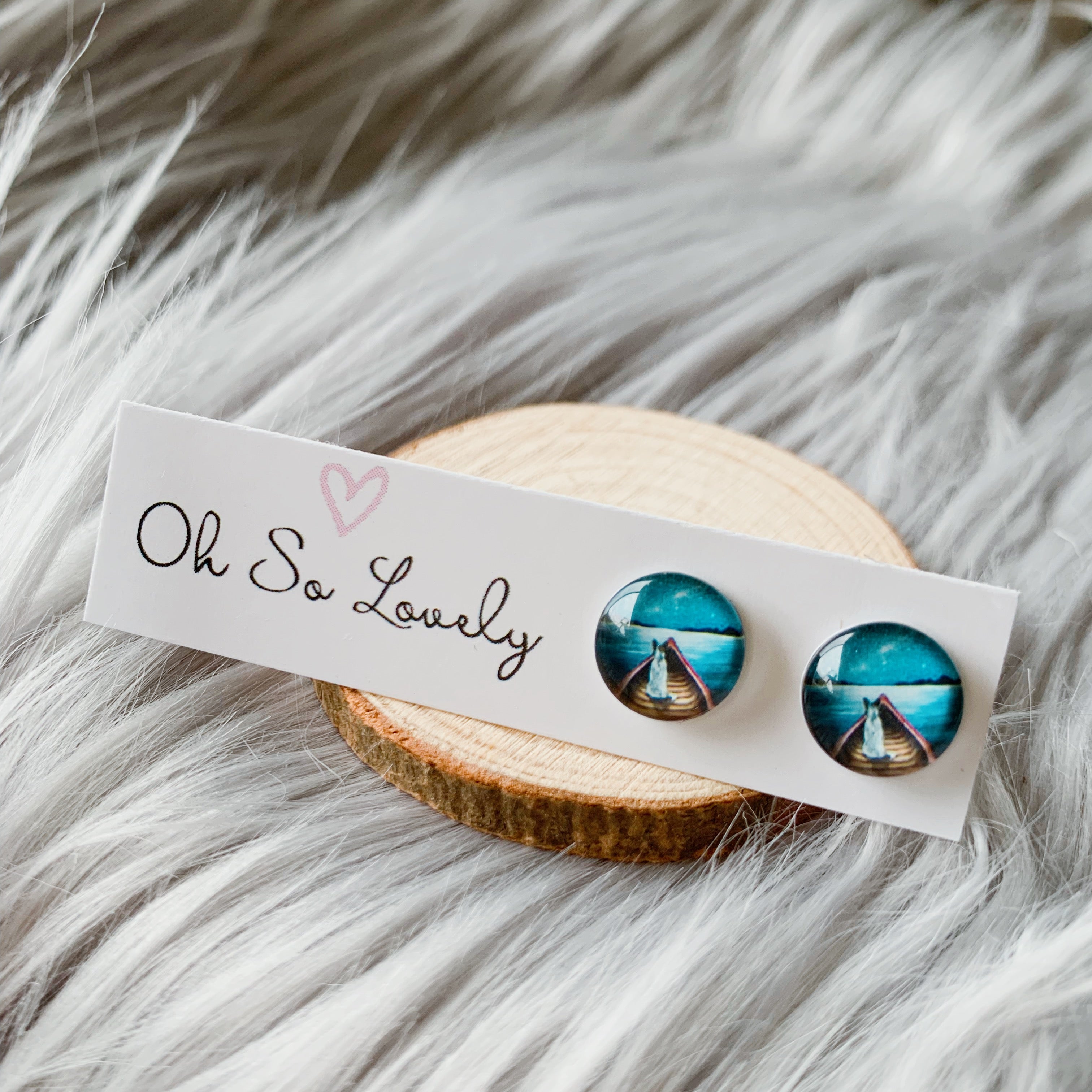 Pair of earrings with dog in a boat design on a 'Oh So Lovely' card against a fur background