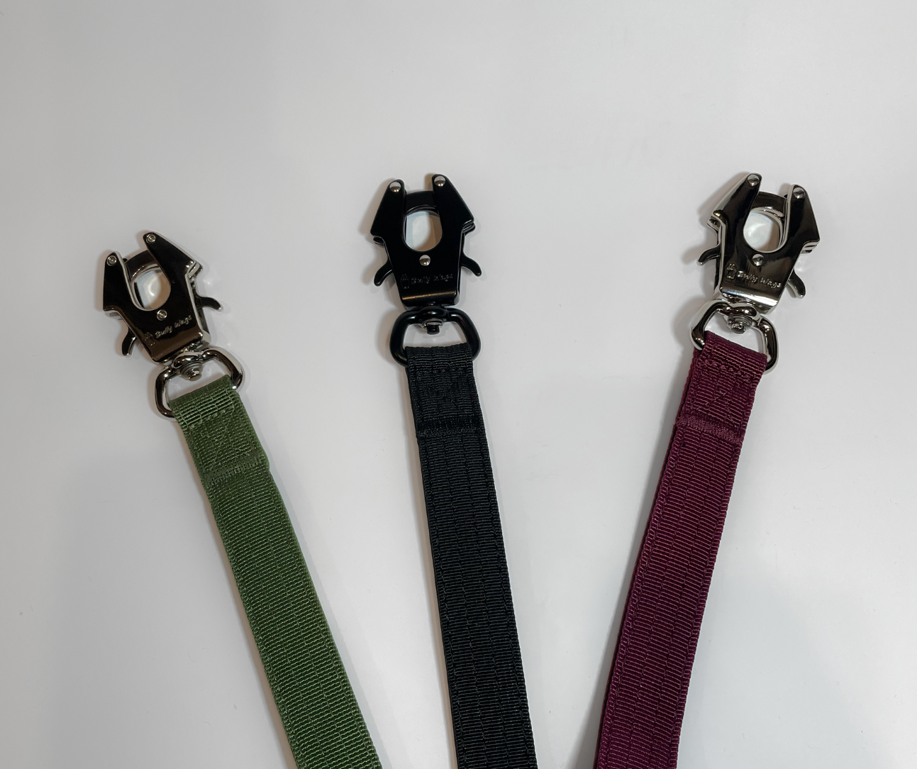 Three dog leash in green, black, and purple with metal clasps on a white background.