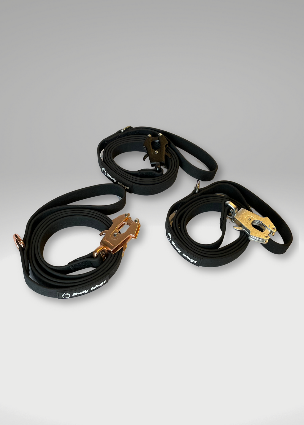 Three black dog leash with gold buckles on a gray background