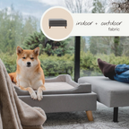 Dog on a gray pet bed with outdoor scenery in the background