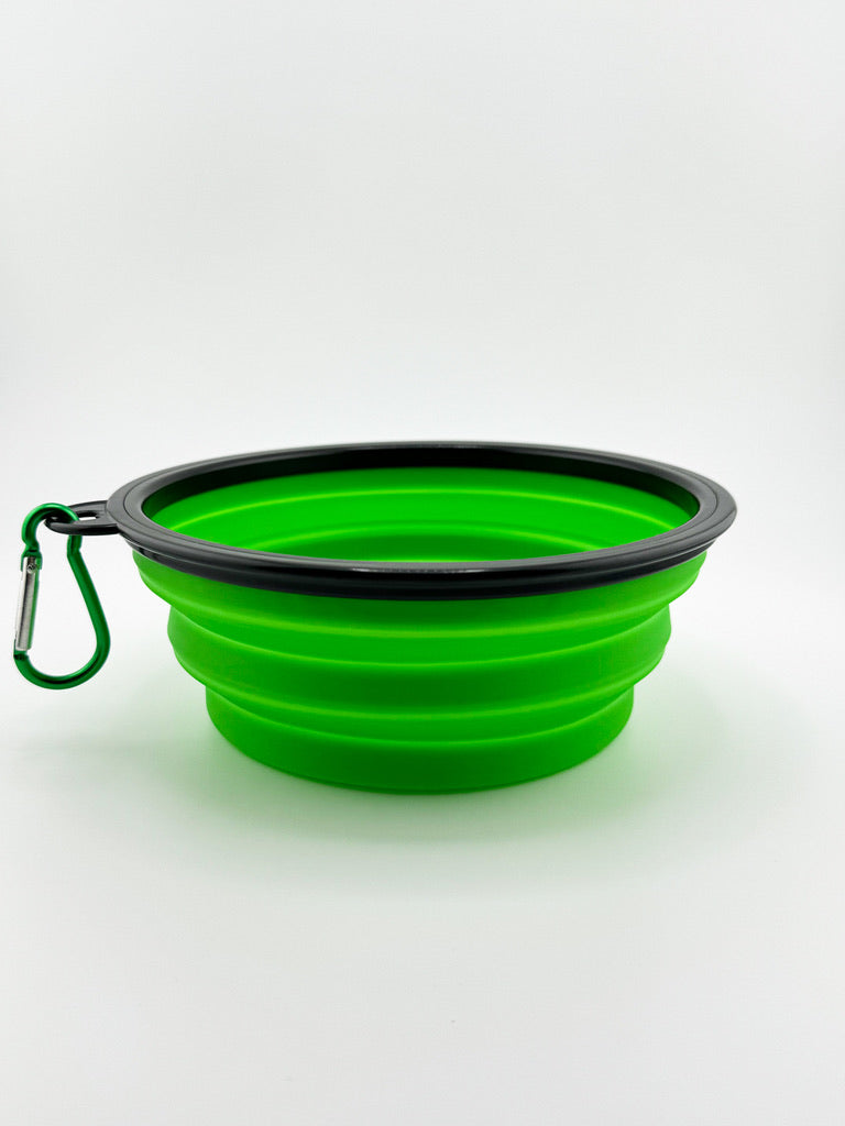Green collapsible silicone dog bowl with black rim and carabiner on a white background