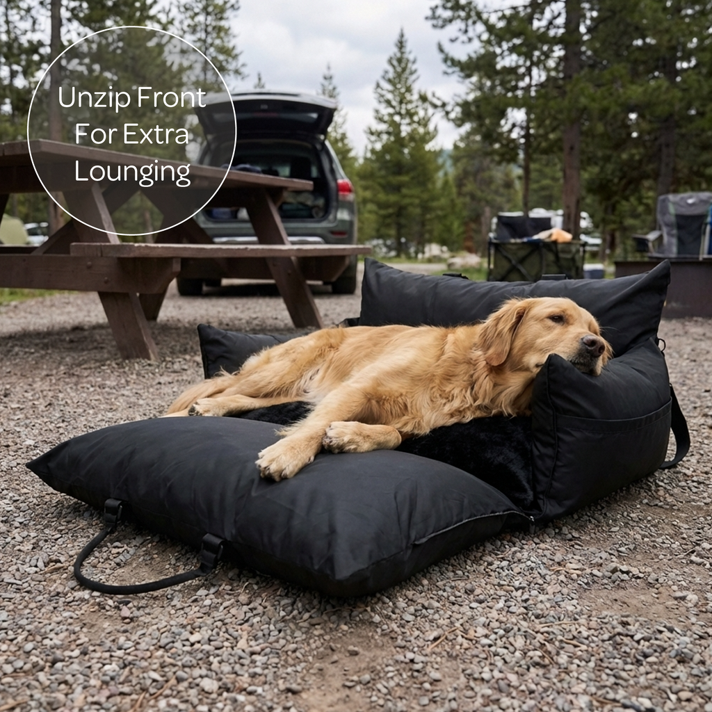 Dog lying on a black pet bed at a campground with text 'Unzip Front For Extra Lounging'.
