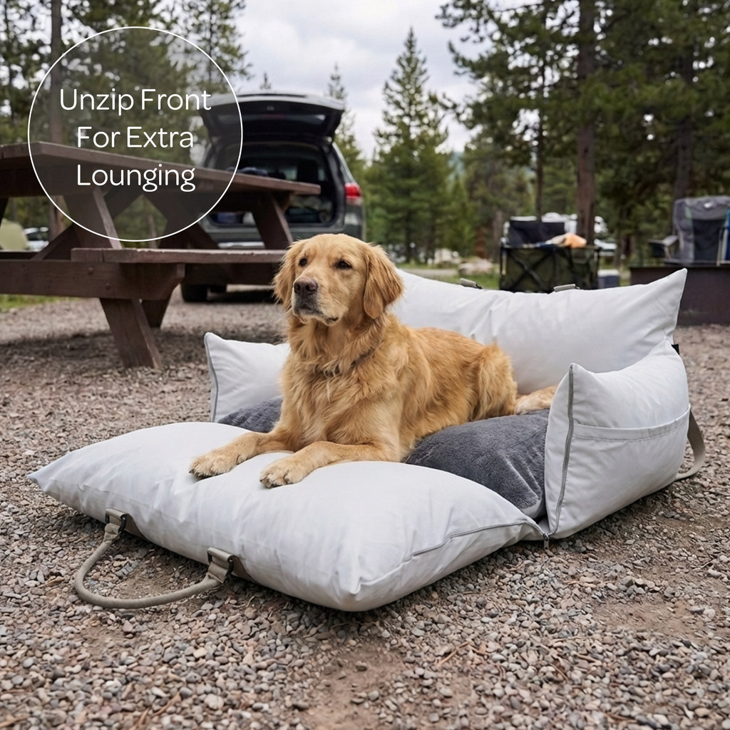 Dog lying on a large outdoor pet bed with a campsite in the background