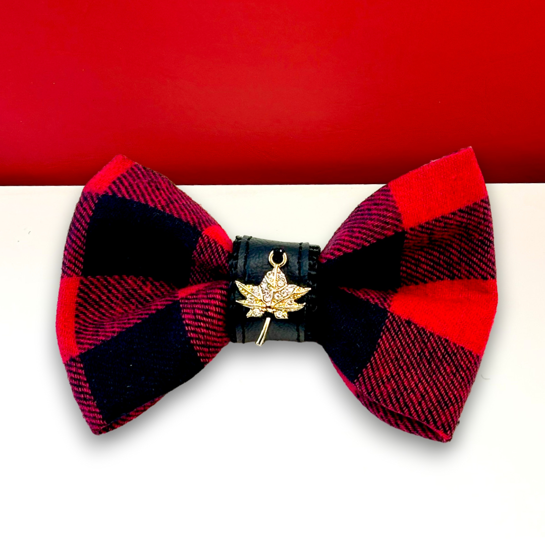 Red and black plaid bow tie with a gold leaf charm on a red background
