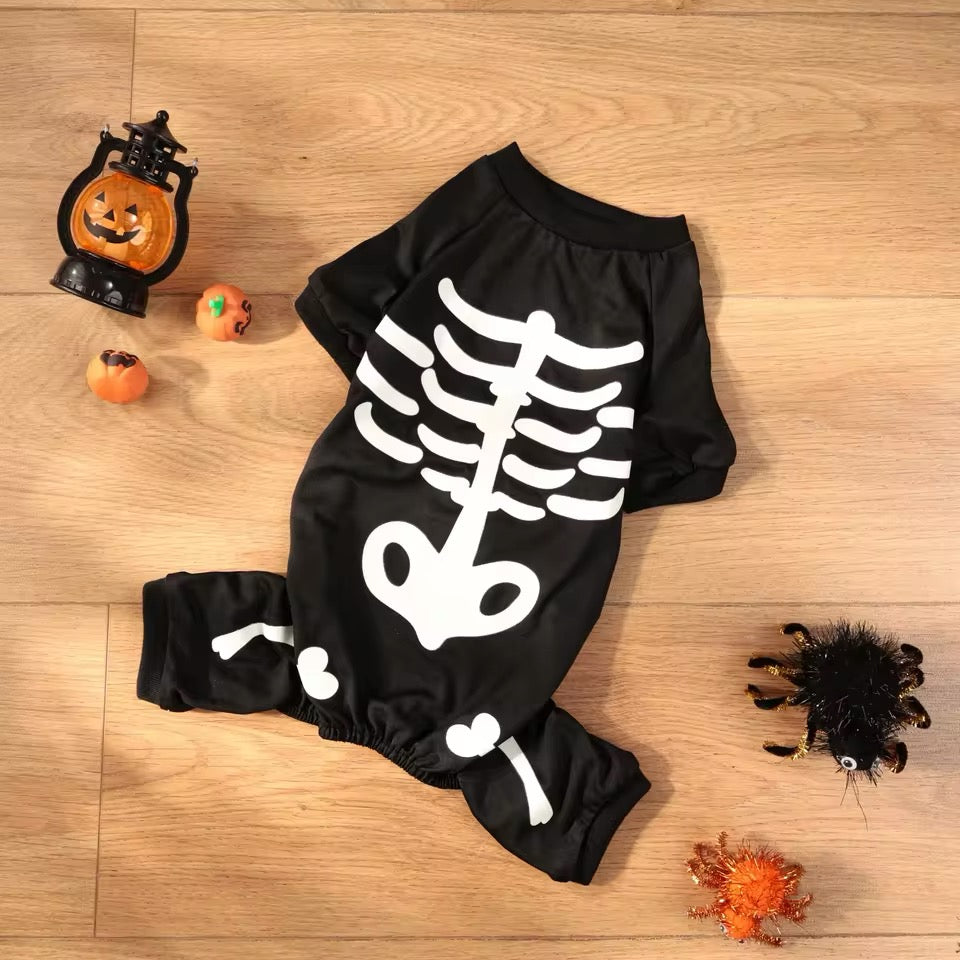 Black baby romper with skeleton design on a wooden floor with Halloween decorations.