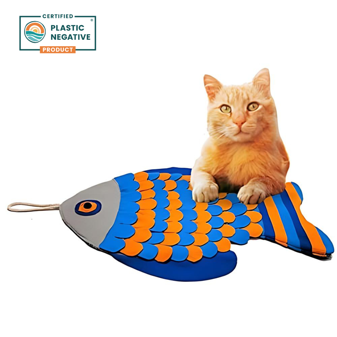 Cat playing with a fish-shaped snuffle mat on a white background, with a 'Plastic Negative' certification logo.