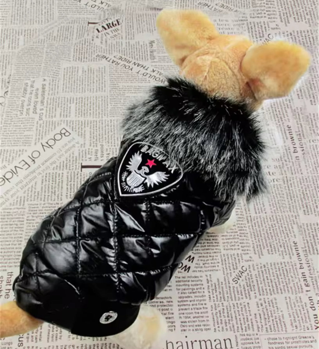 Black puffer jacket with fur hood on a toy bear, placed on a newspaper background.
