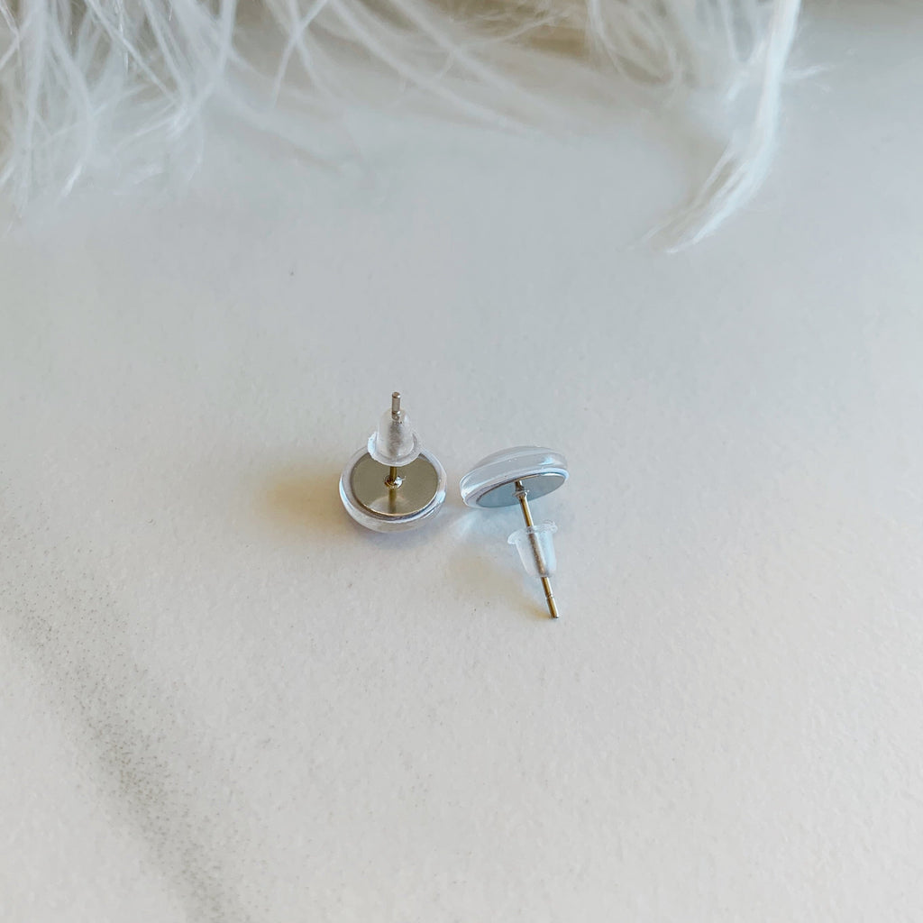 Silver earring on a white feather background