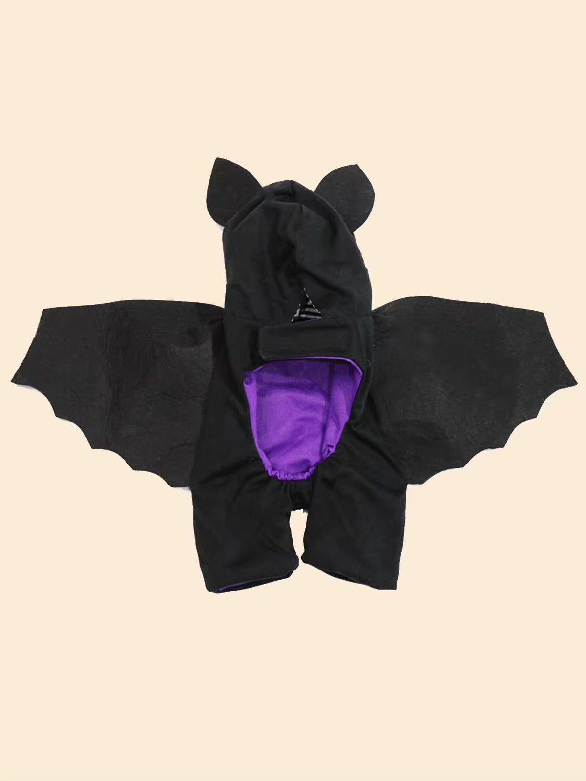 Black bat-shaped costume with purple interior on a beige background