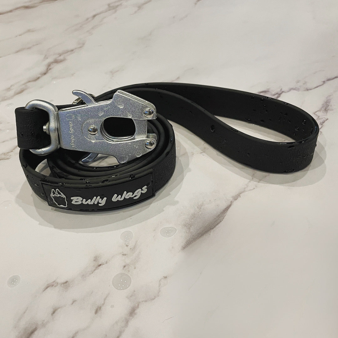 Black dog leash with metal clip on a marble surface