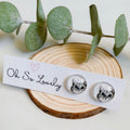 Cat-themed earrings on a wooden block with eucalyptus leaves