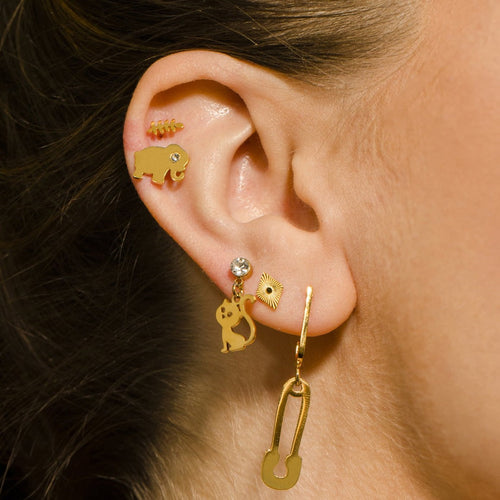 Close-up of an ear wearing gold earrings with elephant and other designs.