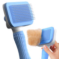Blue pet grooming brush with a hand holding it on a white background