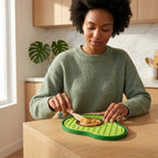 Woman in a kitchen spreading peanut butter on a green lick mat.