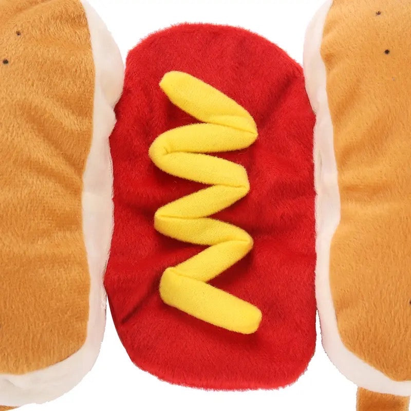 Plush hot dog toy with bun, red body, and yellow mustard on a white background