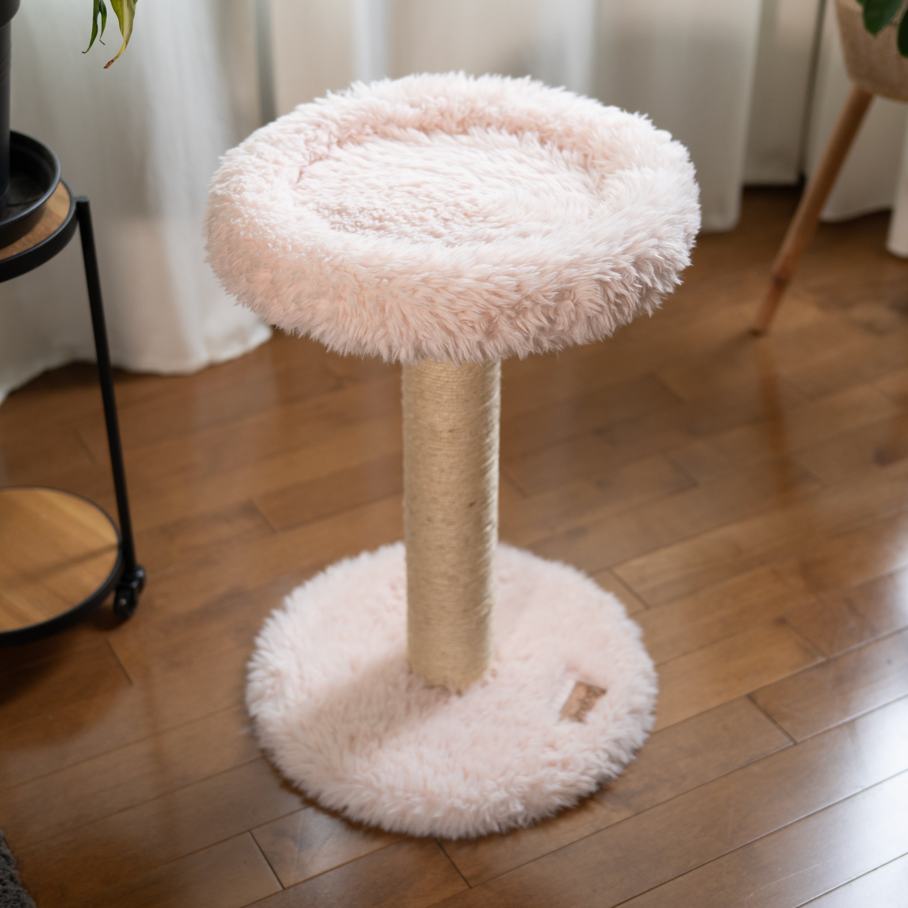 Fluffy cat tree with a round platform on a wooden floor.
