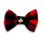 Red and black plaid bow tie with a gold leaf emblem on a white background