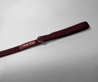 Maroon dog leash with a silver ring on a light gray background