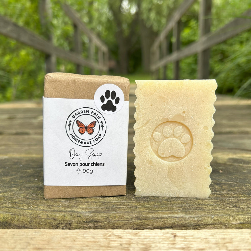 Dog soap bar and packaging with paw print design on a wooden surface outdoors.
