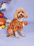 Dog wearing an orange Halloween-themed outfit with pumpkins and ghosts in the background.