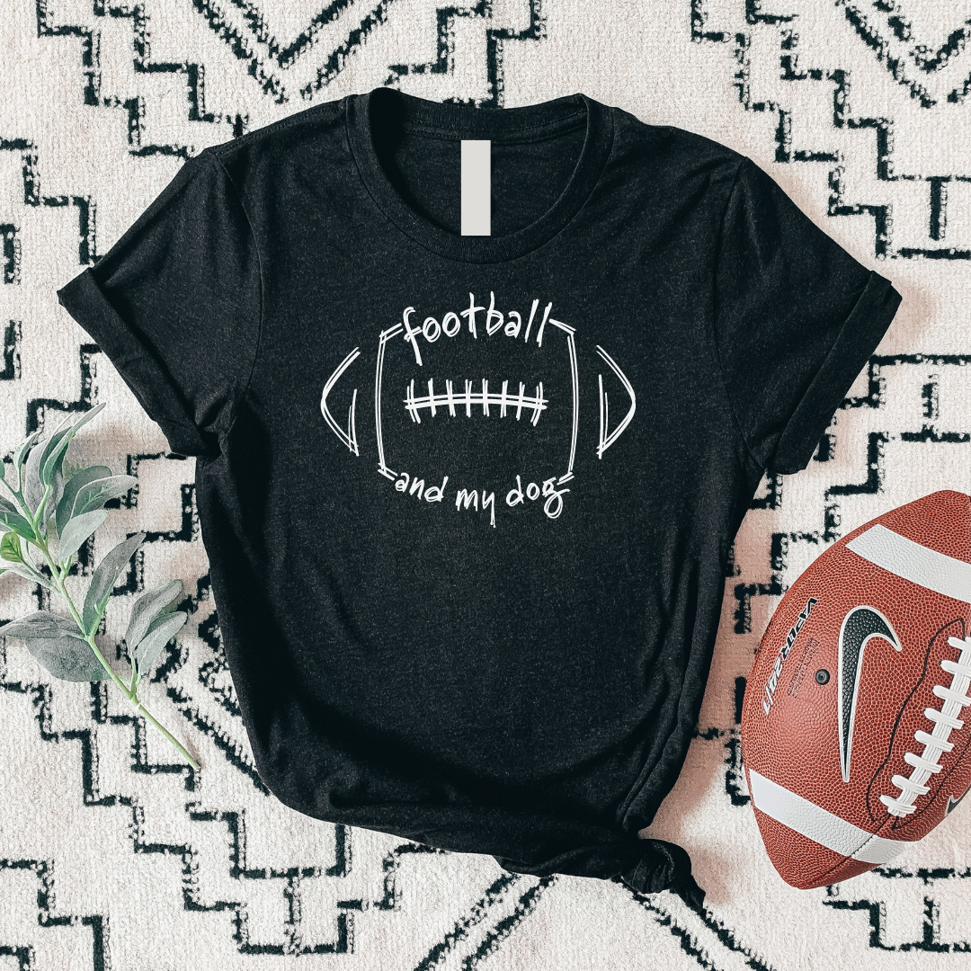 Black t-shirt with 'football and my dog' text on a patterned surface with a football beside it.