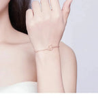 Rose gold bracelet on a person's wrist with a plain background