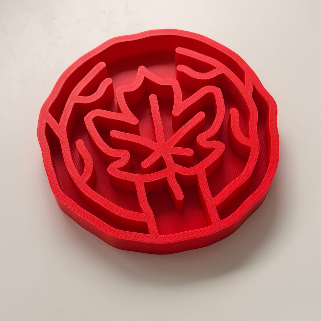 A bright red slow feeding bowl with maple leaf design, shown on a clean white background.