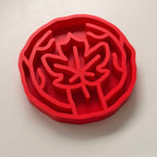 A bright red slow feeding bowl with maple leaf design, shown on a clean white background.