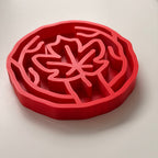A red slow feeding bowl with maple leaf design, shown on a clean white background.