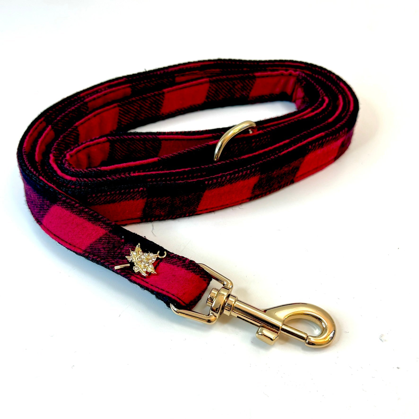Red and black plaid dog leash with gold hardware on a white background