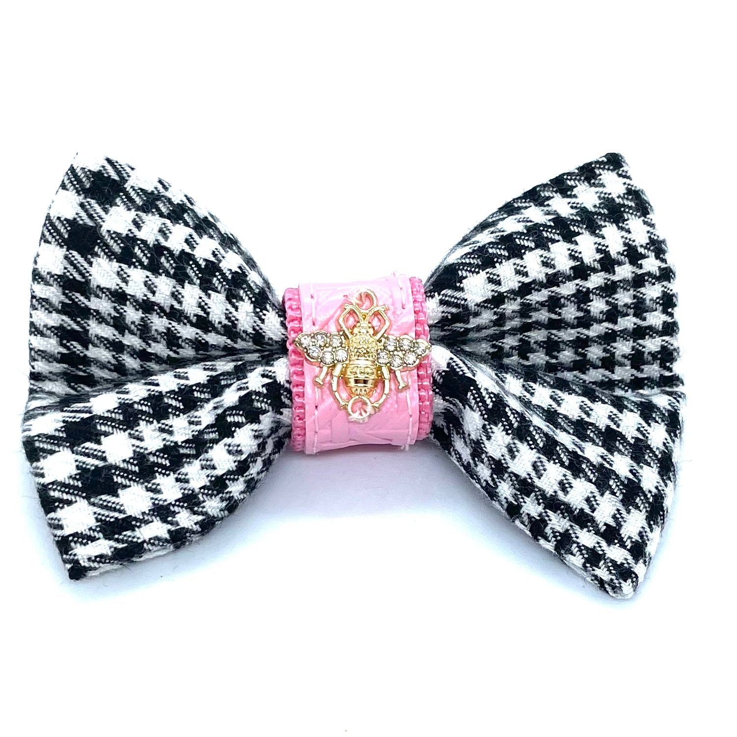 Black and white houndstooth patterned bow with pink center and gold emblem on a white background