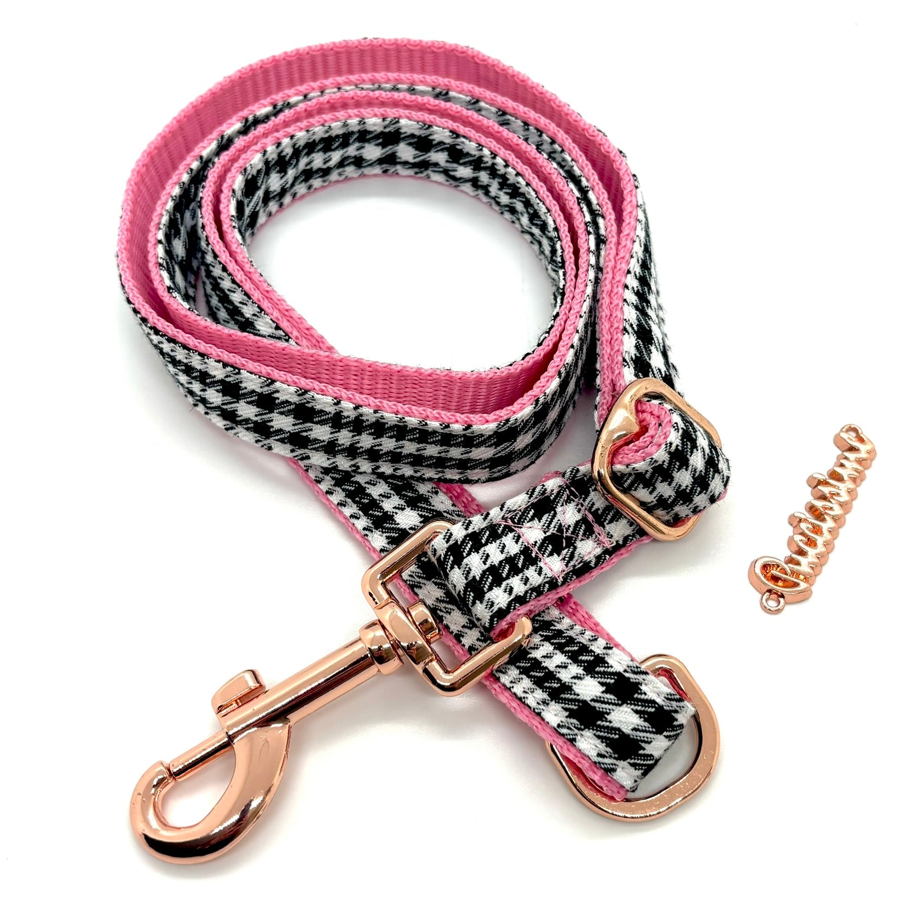 Dog leash with houndstooth pattern and pink accents on a white background