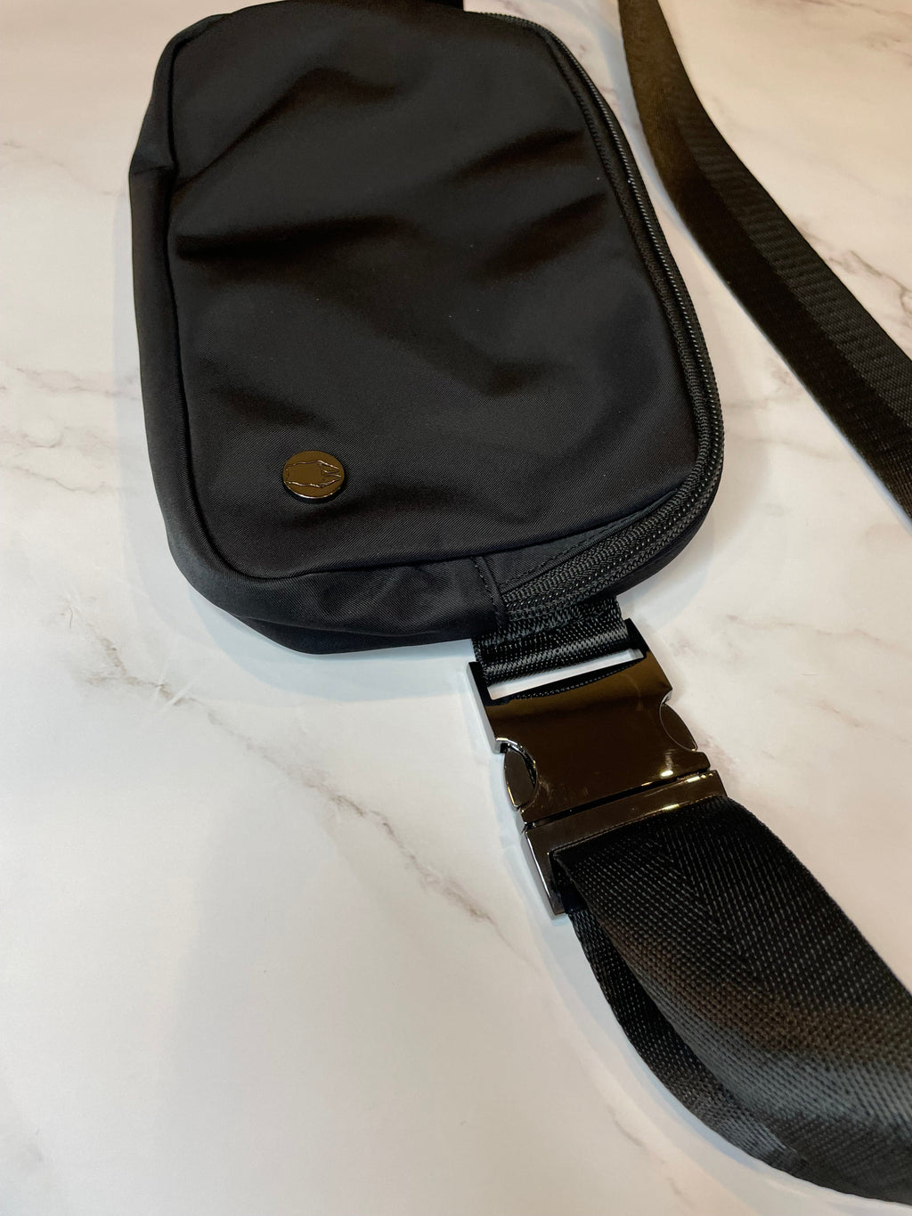 Black dog walk waist bag with a strap on a light marble background