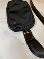 Black dog walk waist bag with a strap on a light marble background