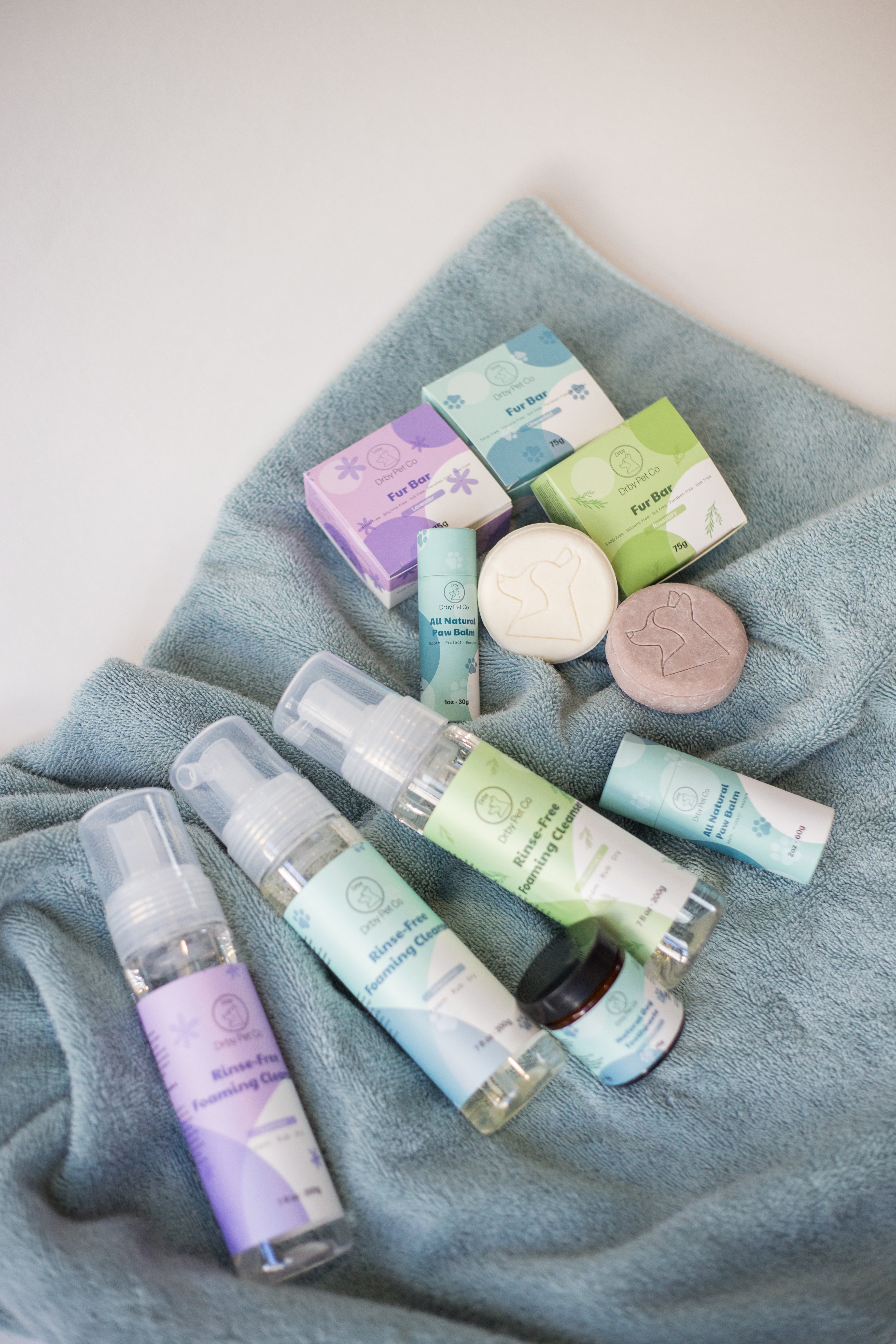 Pet Rince-Free Foaming pet products including bottles, boxes, and soaps on a blue towel