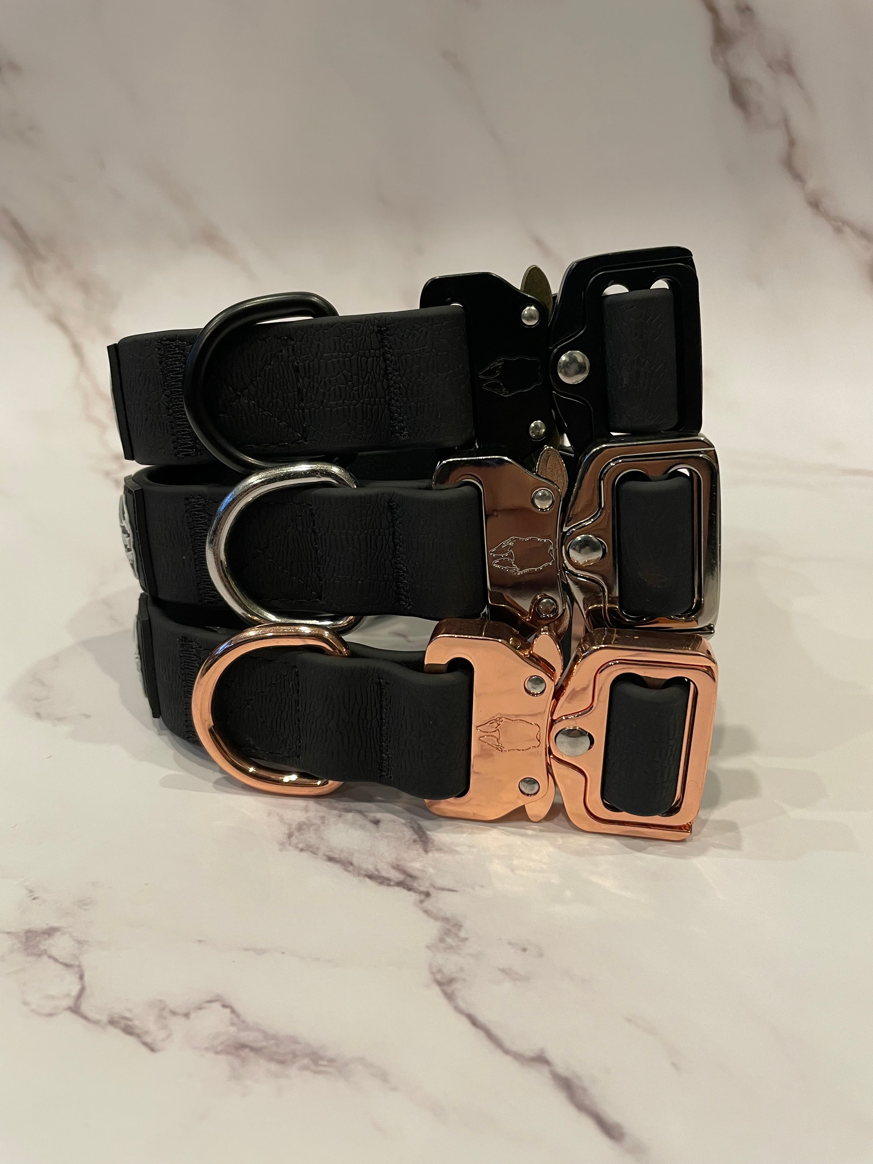 3 black dog collars on a grey background
