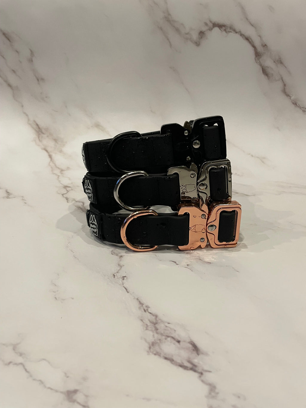 3 black dog collars on a grey background