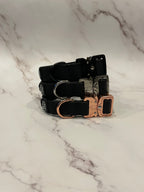 3 black dog collars on a grey background