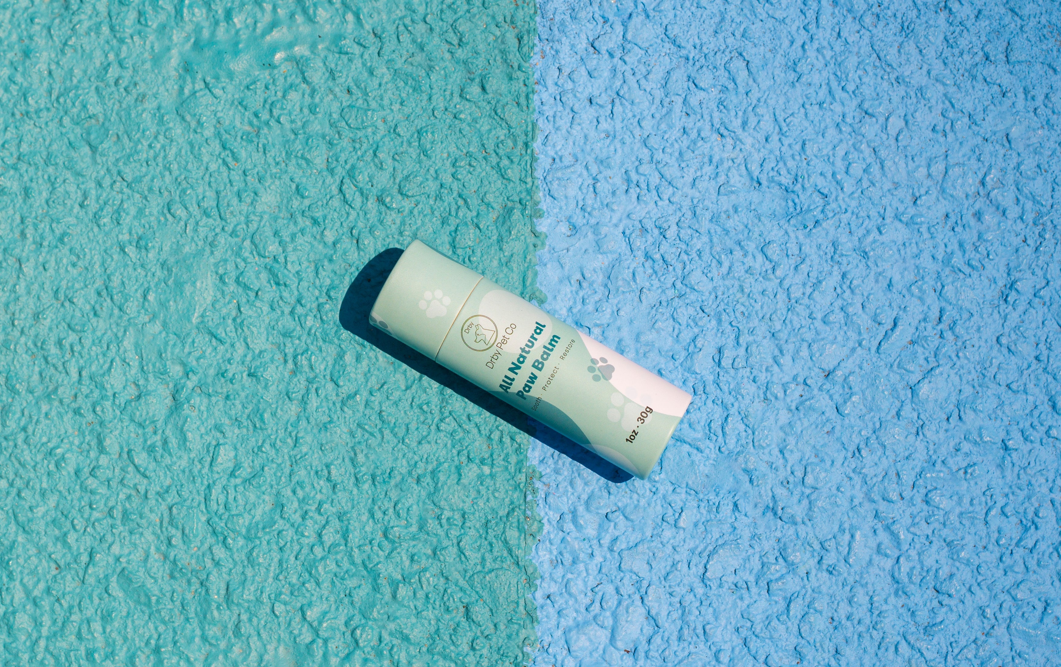 Paw balm tube on a textured blue and green background