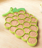 Green pet lick mat shaped like a bunch of grapes on a wooden surface