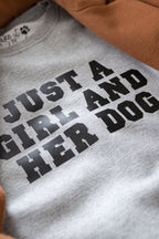 Gray sweatshirt with 'Just a girl and her dog' text on a brown surface