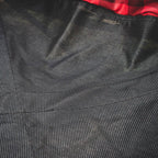 Close-up of textured black fabric with a red plaid pattern at the top.