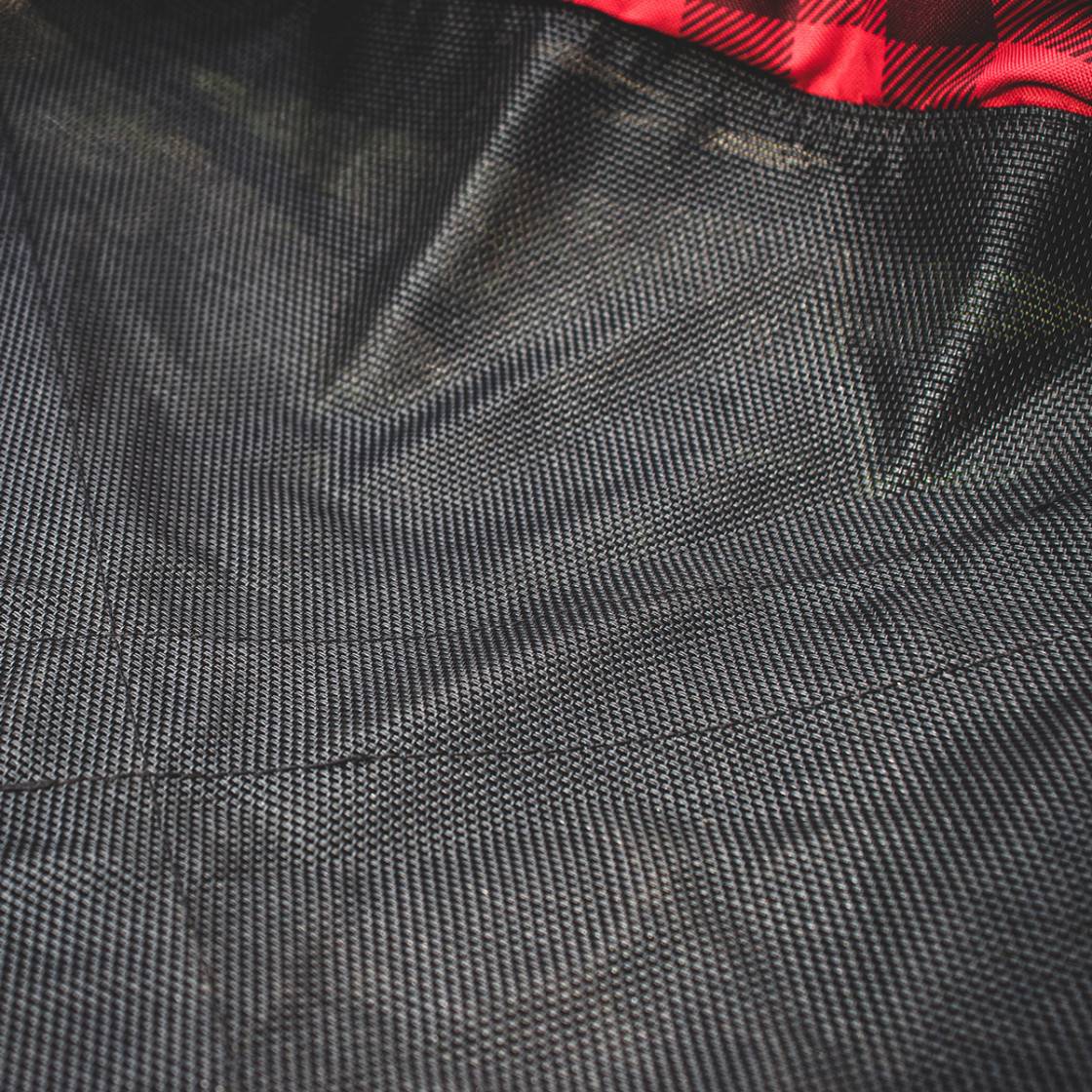 Close-up of textured black fabric with a red plaid pattern at the top.