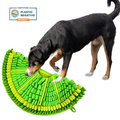 Dog playing with a green and yellow dog toy on a white background, with a 'Plastic Negative' product certification logo.